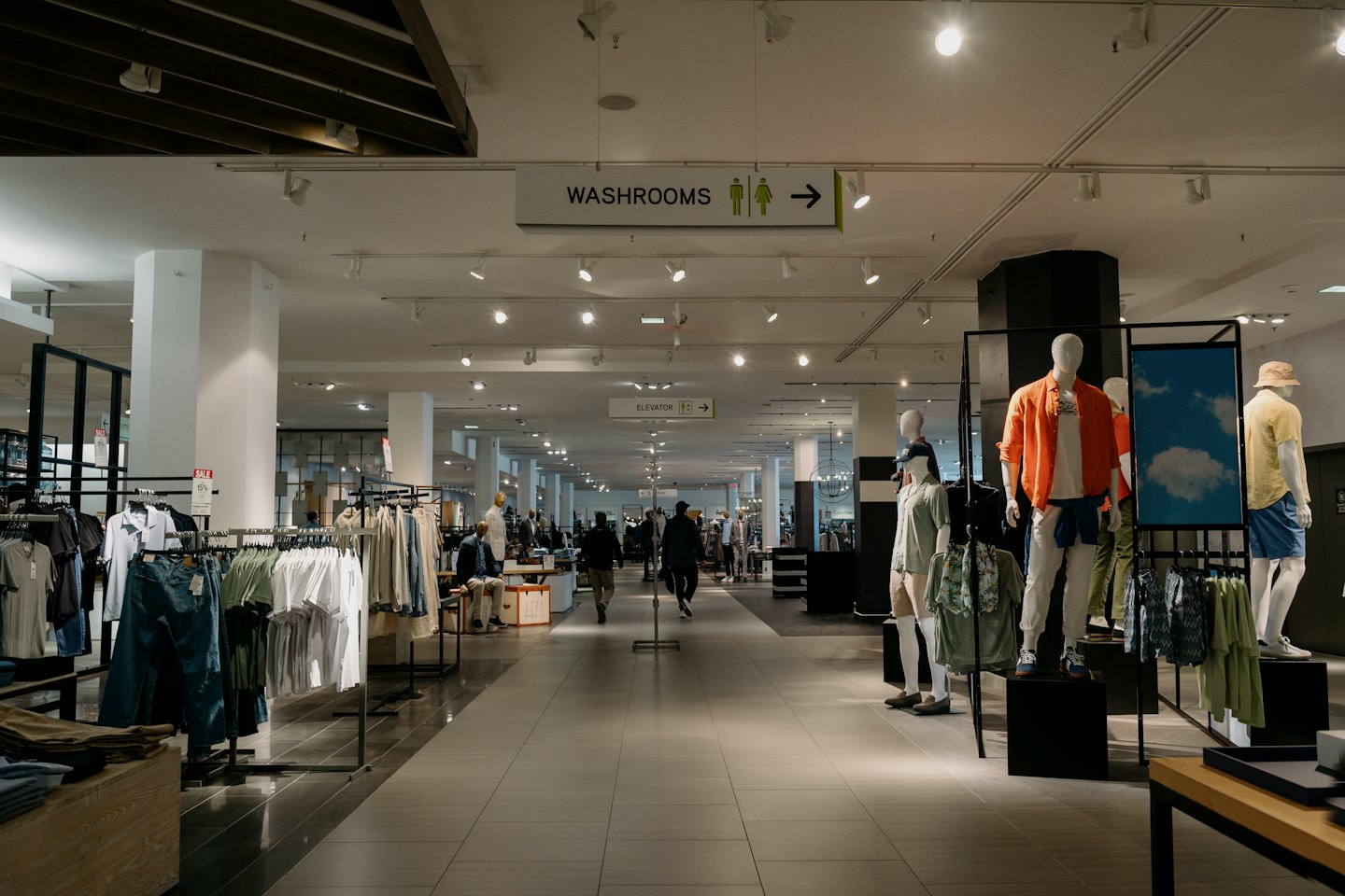 Modern department store with men's clothing on racks and mannequins.